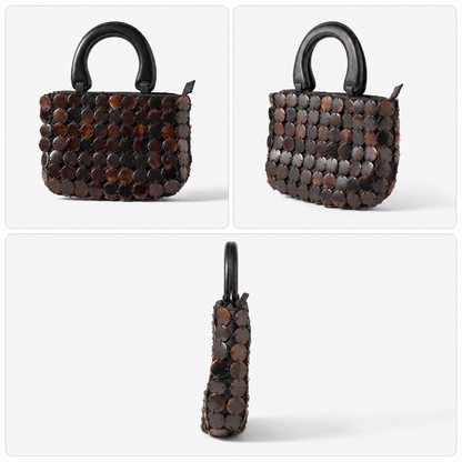 The Marlowe shell bag carried by its carved wooden handle, small enough to pack flat and take travelling.